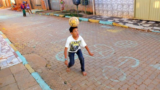 Un ni�o juega f�tbol en una calle polvorienta en la favela Vila Estrutural en Brasilia. 