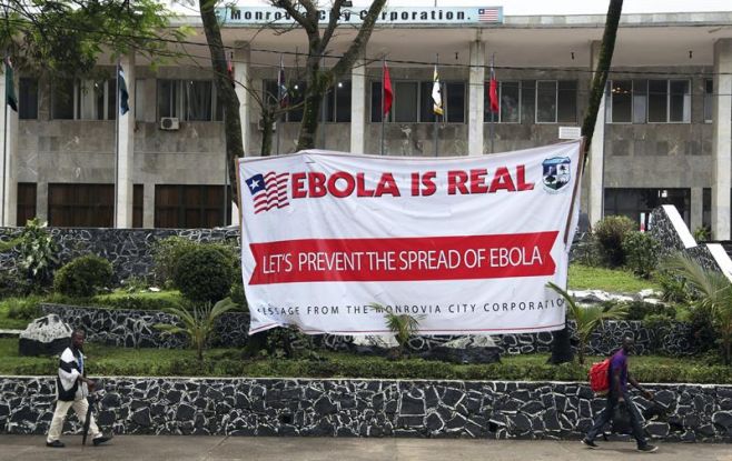 otografa de archivo fechada el pasado 31 de julio del 2014 que muestra a varios liberianos caminando frente a un cartel que alerta sobre los peligros del bola en el Ayuntamiento de Monrovia (Liberia). Liberia afronta hoy, jueves 7 de agosto del 2014,. EFE