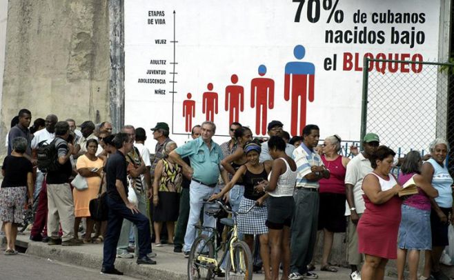 Foto de archivo, fechada en La Habana (Cuba) el 26 de noviembre de 2004, en la que un grupo de personas hace cola ante una Casa de Cambios (CADECA) para cambiar d�lares por pesos cubanos. Al fondo, un cartel contra el bloqueo de EEUU a Cuba. El president. EFE