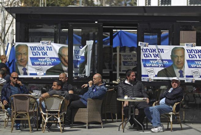 Varias personas se sientan en una cafeter�a con carteles electorales del partido Likud, en las que se muestra al primer ministro israel�, Benjam�n Netanyahu, scon motivo las elecciones generales israel�es, en la ciudad de Ashkel�n, Israel, hoy, marte. EFE